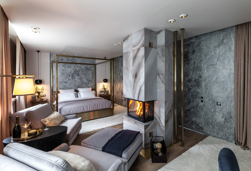 Photo of a contemporary master bedroom in Moscow with grey walls, a standard fireplace, a stone fireplace surround and medium hardwood floors.
