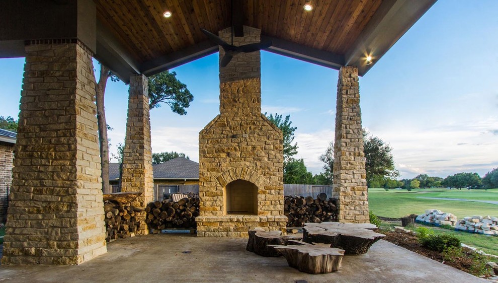 Inspiration for a backyard verandah in Dallas with a fire feature, stamped concrete and a roof extension.