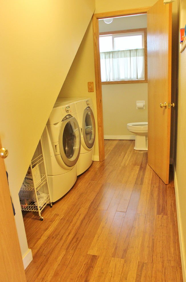 This is an example of a small country single-wall utility room in Seattle with beige walls, light hardwood floors and a side-by-side washer and dryer.
