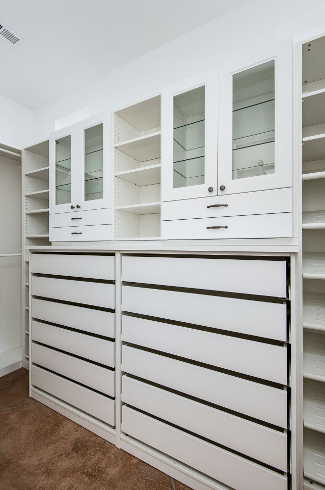 This is an example of a large country gender-neutral walk-in wardrobe in Portland with shaker cabinets, white cabinets, concrete floors and brown floor.