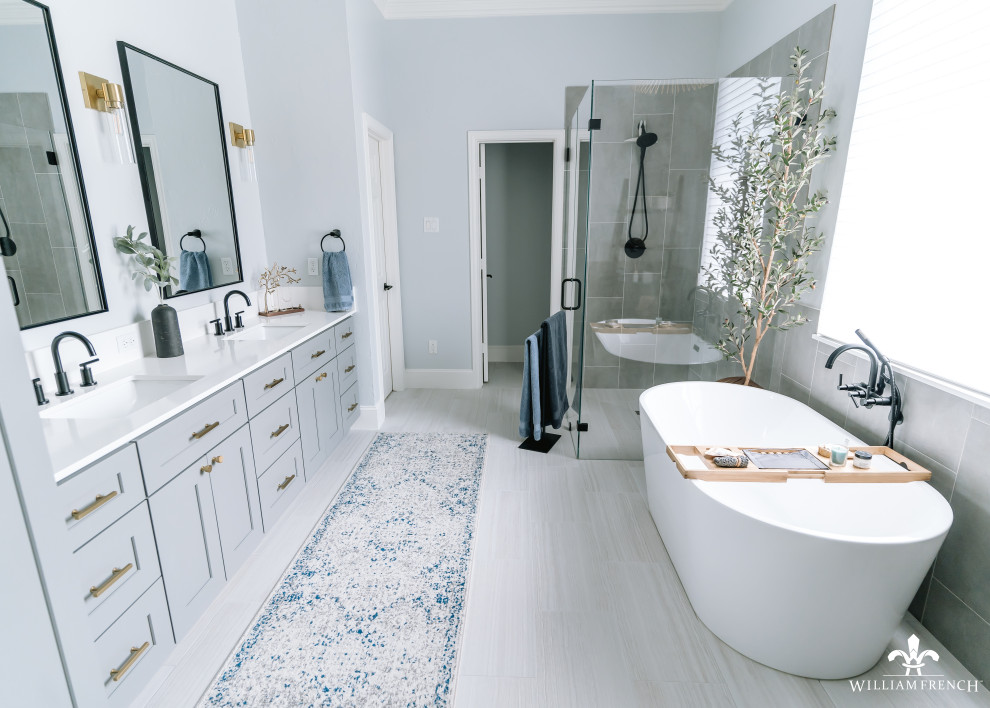 Exemple d'une salle de bain principale bord de mer de taille moyenne avec un placard à porte shaker, des portes de placard grises, une baignoire indépendante, une douche d'angle, WC séparés, un carrelage gris, des carreaux de porcelaine, un mur bleu, un sol en carrelage de porcelaine, un lavabo encastré, un plan de toilette en quartz modifié, un sol gris, une cabine de douche à porte battante, un plan de toilette blanc, un banc de douche, meuble double vasque et meuble-lavabo encastré.