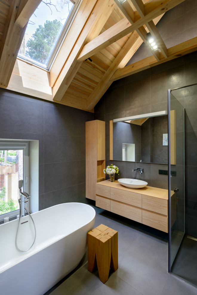 Photo of a mid-sized asian 3/4 bathroom in Novosibirsk with flat-panel cabinets, light wood cabinets, a freestanding tub, gray tile, a vessel sink, wood benchtops, grey floor, an open shower, beige benchtops and a corner shower.