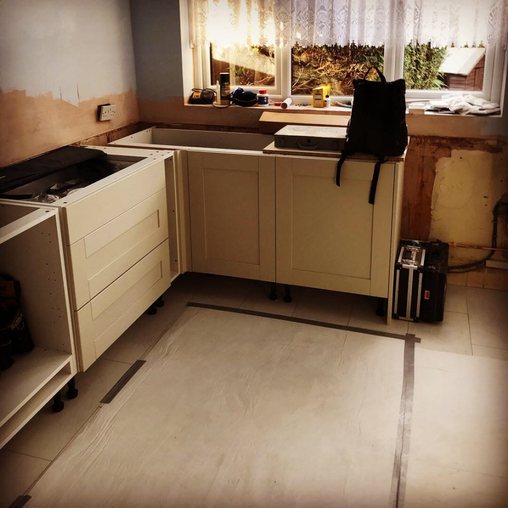 ロンドンにある高級な広いヴィクトリアン調のおしゃれなキッチン (ダブルシンク、シェーカースタイル扉のキャビネット、白いキャビネット、ラミネートカウンター、赤いキッチンパネル、セラミックタイルのキッチンパネル、パネルと同色の調理設備、磁器タイルの床、マルチカラーの床、白いキッチンカウンター) の写真