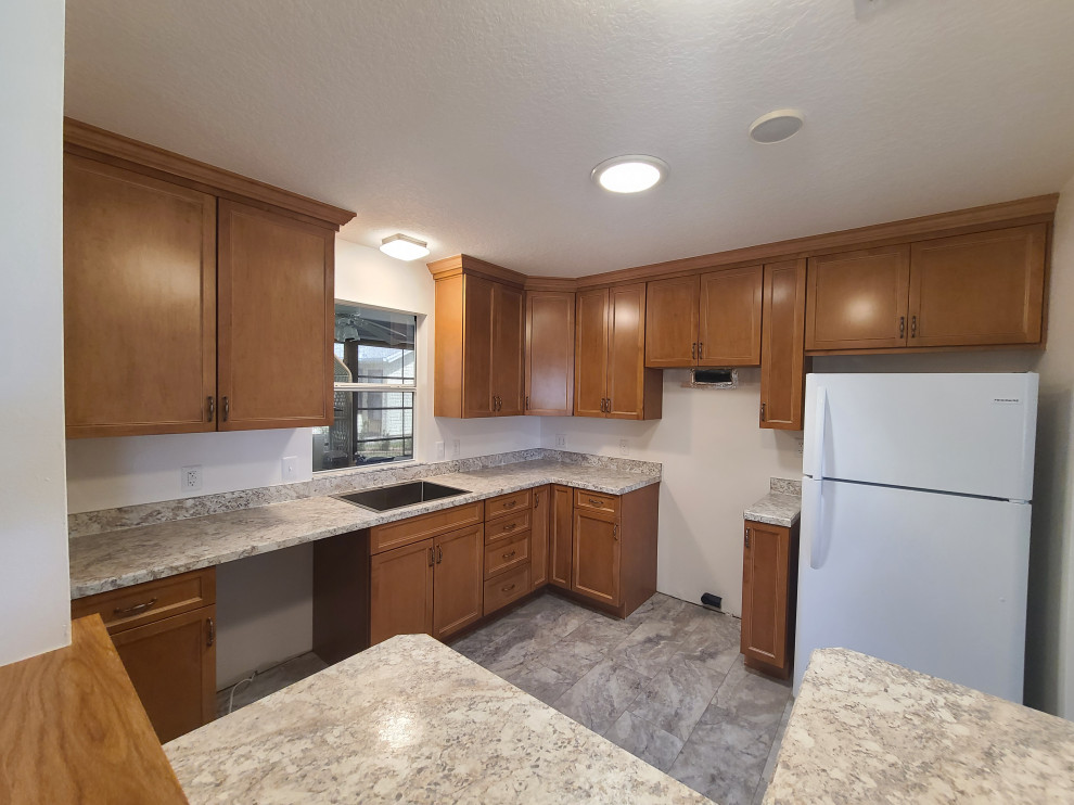 Mid-sized l-shaped eat-in kitchen photo with flat-panel cabinets, medium tone wood cabinets, laminate countertops, an island and white countertops