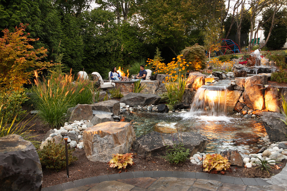 Photo of a large traditional backyard full sun formal garden in Seattle with a water feature and natural stone pavers.