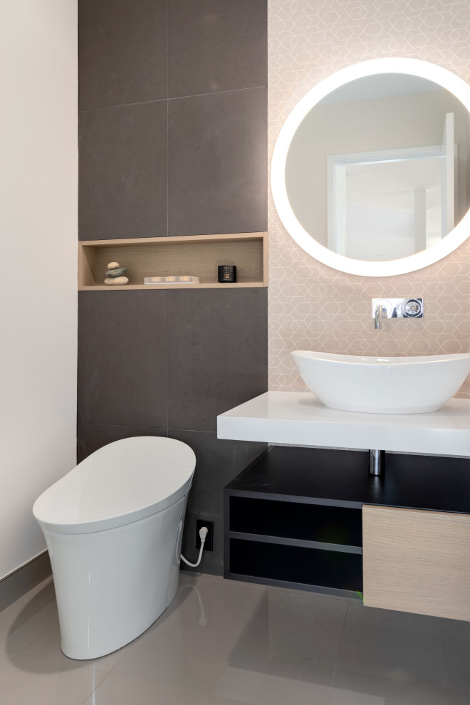 Inspiration for a mid-sized contemporary powder room in Tampa with flat-panel cabinets, light wood cabinets, a one-piece toilet, porcelain tile, beige walls, porcelain floors, a vessel sink, engineered quartz benchtops, grey floor and white benchtops.