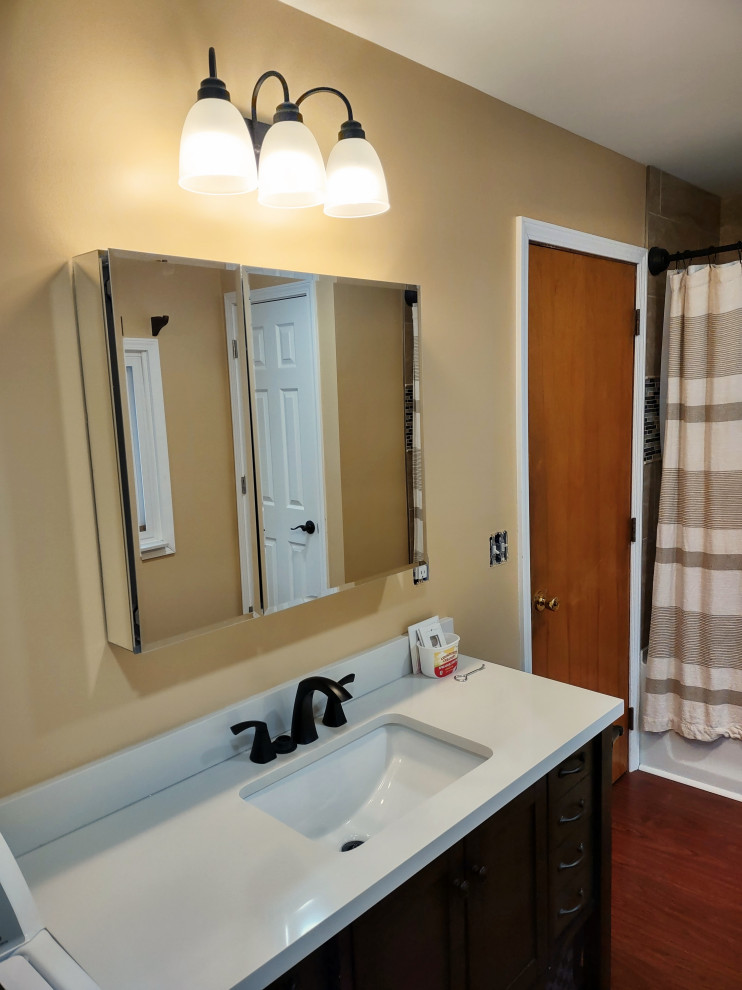 Exempel på ett mellanstort klassiskt beige beige en-suite badrum, med luckor med infälld panel, skåp i mörkt trä, ett platsbyggt badkar, en dusch/badkar-kombination, en toalettstol med separat cisternkåpa, laminatgolv, ett nedsänkt handfat, laminatbänkskiva, brunt golv, dusch med duschdraperi och orange väggar