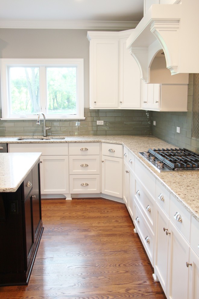 Large transitional u-shaped medium tone wood floor eat-in kitchen photo in Chicago with a double-bowl sink, shaker cabinets, white cabinets, granite countertops, green backsplash, glass tile backsplash, stainless steel appliances and an island