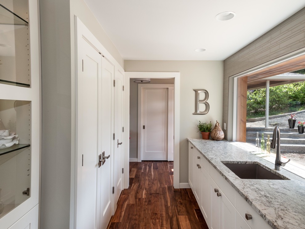 Inspiration for a mid-sized transitional l-shaped kitchen pantry in Seattle with an undermount sink, shaker cabinets, white cabinets, quartz benchtops, grey splashback, stainless steel appliances, medium hardwood floors and with island.