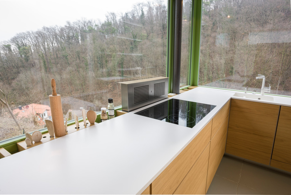 Küche ohne Insel in U-Form mit Waschbecken, Glasfronten, hellen Holzschränken, Mineralwerkstoff-Arbeitsplatte, Keramikboden, grauem Boden und weißer Arbeitsplatte