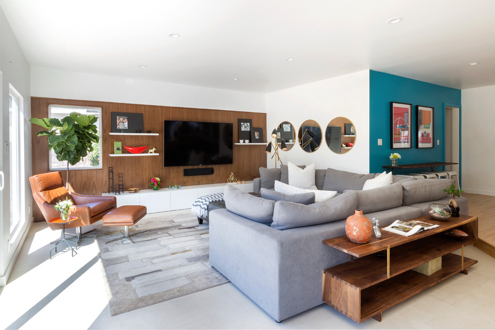 Photo of a mid-sized midcentury open concept family room in Los Angeles with white walls, limestone floors, a wall-mounted tv and beige floor.