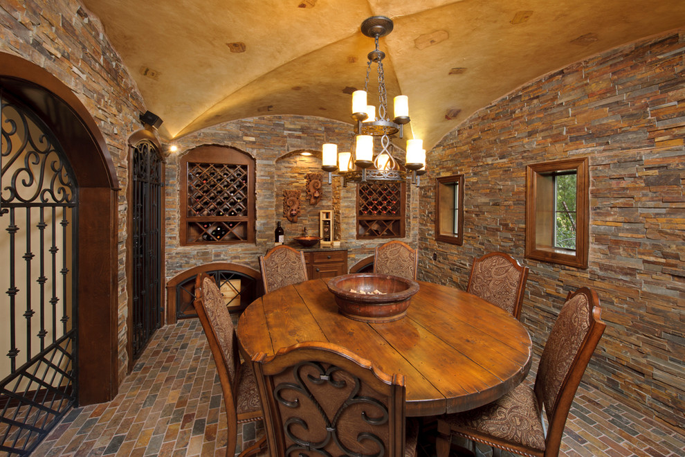 This is an example of a mediterranean wine cellar in Houston with brick floors, storage racks and multi-coloured floor.