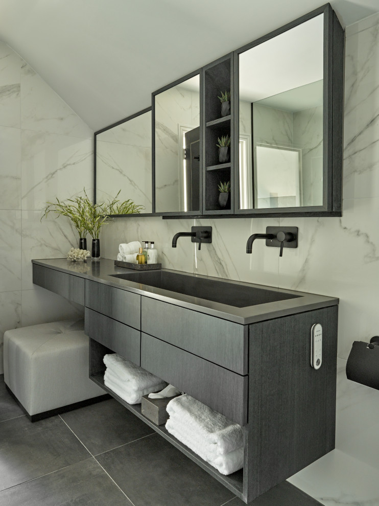 Photo of a contemporary bathroom in London with flat-panel cabinets, grey cabinets, gray tile, white tile, white walls, a trough sink, grey floor, grey benchtops, a double vanity, a floating vanity and vaulted.