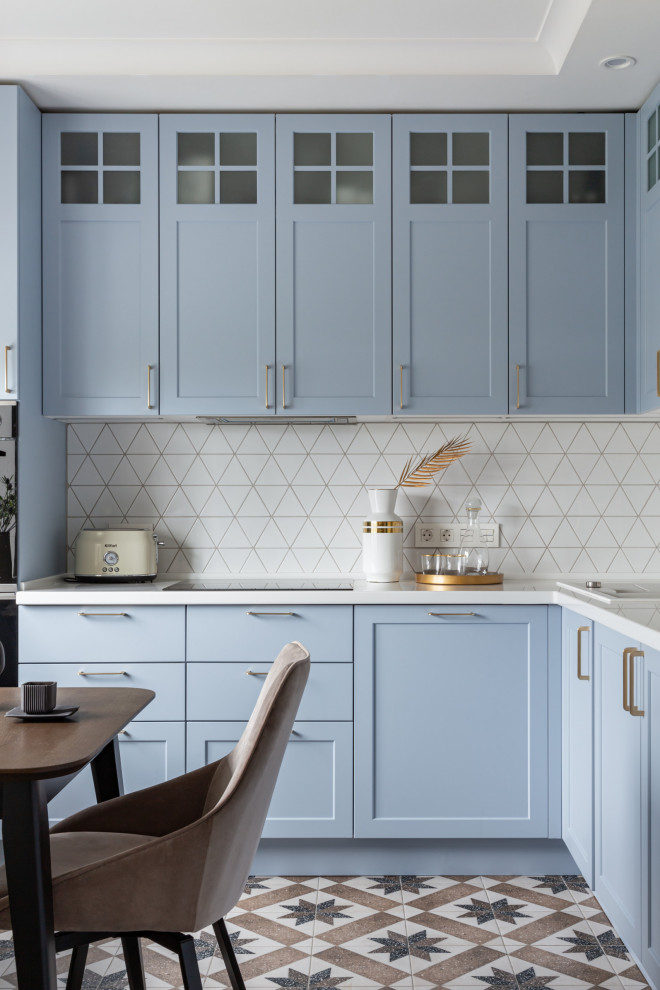 Ejemplo de cocinas en L clásica renovada con armarios estilo shaker, puertas de armario azules, salpicadero blanco, suelo multicolor, encimeras blancas y bandeja