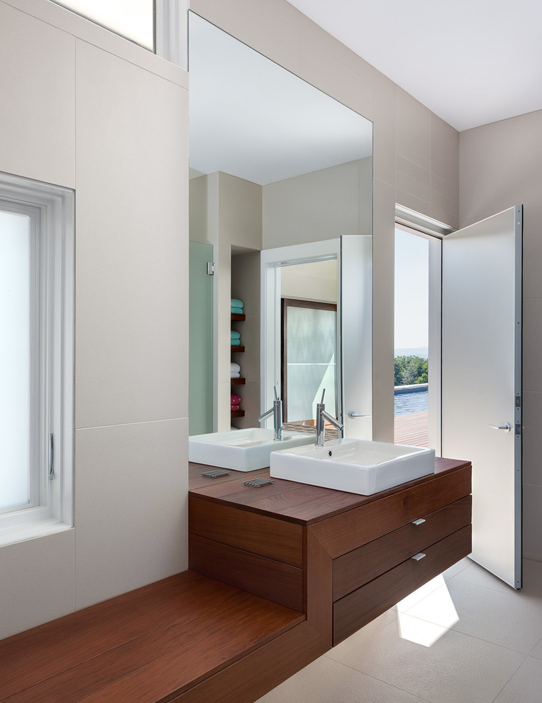 Photo of a mid-sized modern 3/4 bathroom in Bridgeport with a vessel sink, porcelain tile, dark wood cabinets, wood benchtops, beige tile, beige walls, porcelain floors, an alcove shower, a one-piece toilet, beige floor, a hinged shower door and flat-panel cabinets.