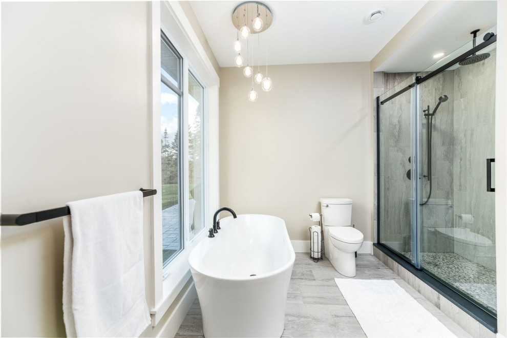 Large transitional master gray tile and ceramic tile ceramic tile and gray floor freestanding bathtub photo with a two-piece toilet, beige walls and a hinged shower door
