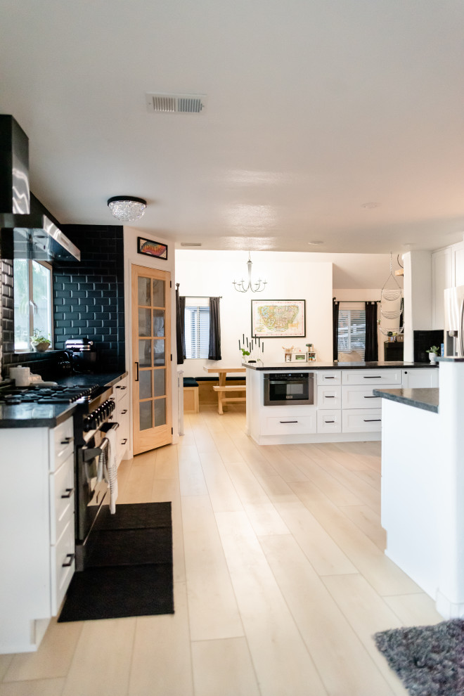 Eat-in kitchen - mid-sized eclectic u-shaped vinyl floor and beige floor eat-in kitchen idea in San Diego with a drop-in sink, beaded inset cabinets, white cabinets, marble countertops, black backsplash, ceramic backsplash, stainless steel appliances, an island and black countertops