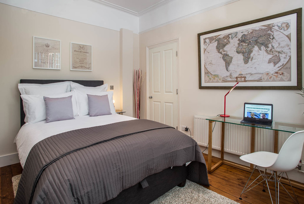 This is an example of a transitional bedroom in London with beige walls and medium hardwood floors.
