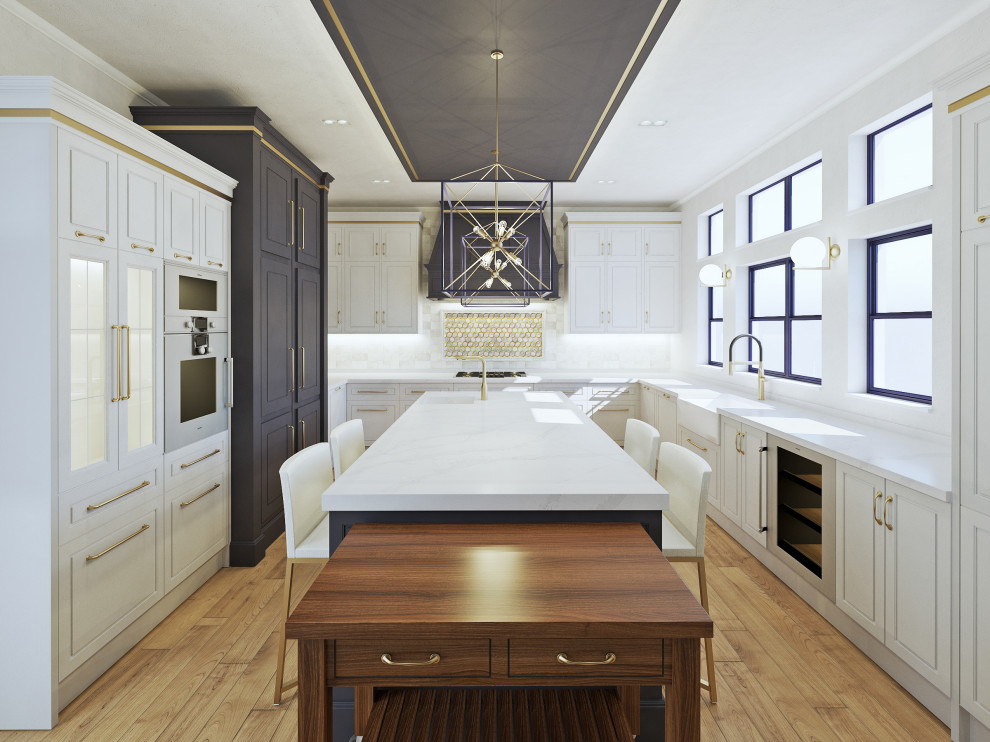This is an example of a large traditional u-shaped separate kitchen in Other with a farmhouse sink, raised-panel cabinets, white cabinets, marble benchtops, white splashback, marble splashback, stainless steel appliances, light hardwood floors, with island, brown floor and white benchtop.