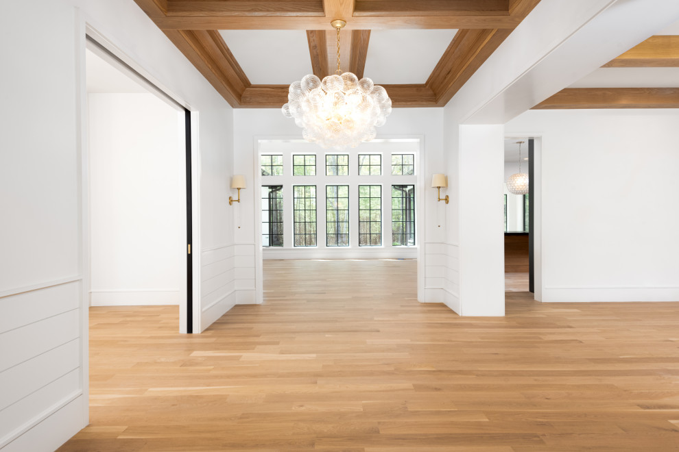 Mid-sized transitional light wood floor, coffered ceiling and shiplap wall entry hall photo with white walls and a black front door