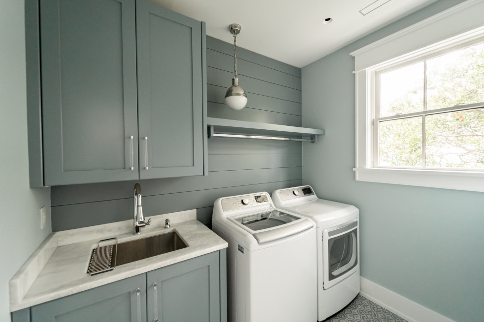 Maritime Waschküche mit Einbauwaschbecken, Schrankfronten im Shaker-Stil, grauen Schränken, Küchenrückwand in Grau, Rückwand aus Holzdielen, blauer Wandfarbe, Waschmaschine und Trockner nebeneinander und grauer Arbeitsplatte in Sonstige