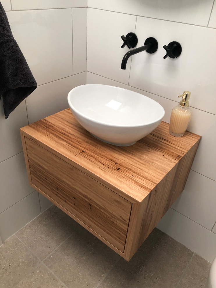 Inspiration for a small contemporary master bathroom in Other with flat-panel cabinets, medium wood cabinets, an alcove shower, a wall-mount toilet, white tile, ceramic tile, white walls, ceramic floors, a vessel sink, wood benchtops, grey floor, a hinged shower door, brown benchtops, a niche, a single vanity and a floating vanity.