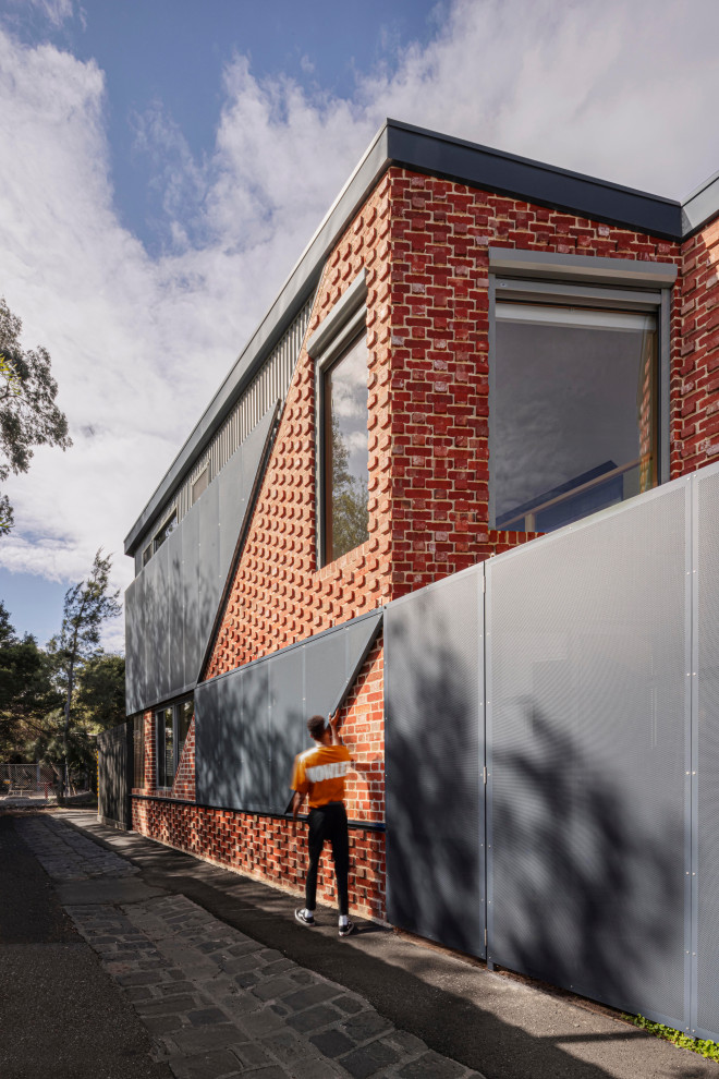 Mid-sized modern two-storey brick red house exterior in Melbourne with a metal roof and a grey roof.