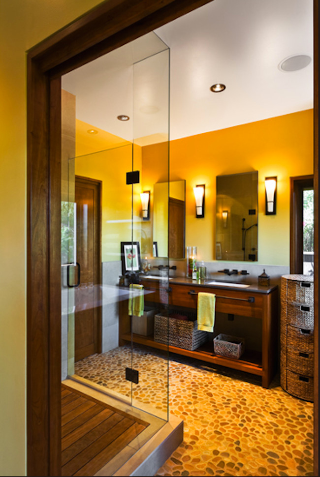 Photo of a mid-sized tropical master bathroom in Santa Barbara with a drop-in sink, medium wood cabinets, a corner shower, gray tile, stone tile, yellow walls and pebble tile floors.