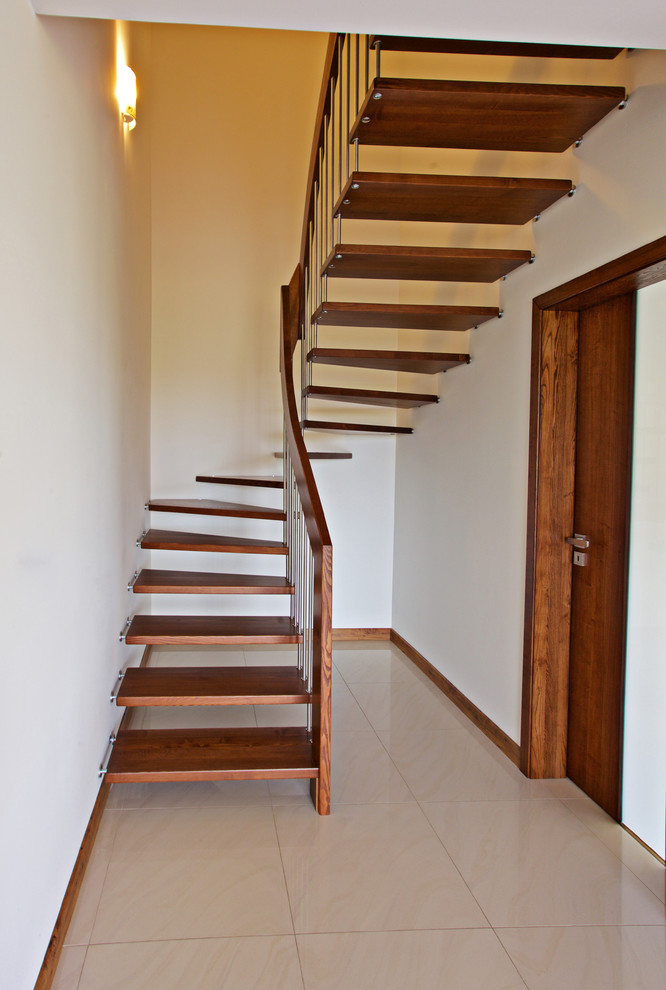 Large contemporary wood curved staircase in Other with open risers.