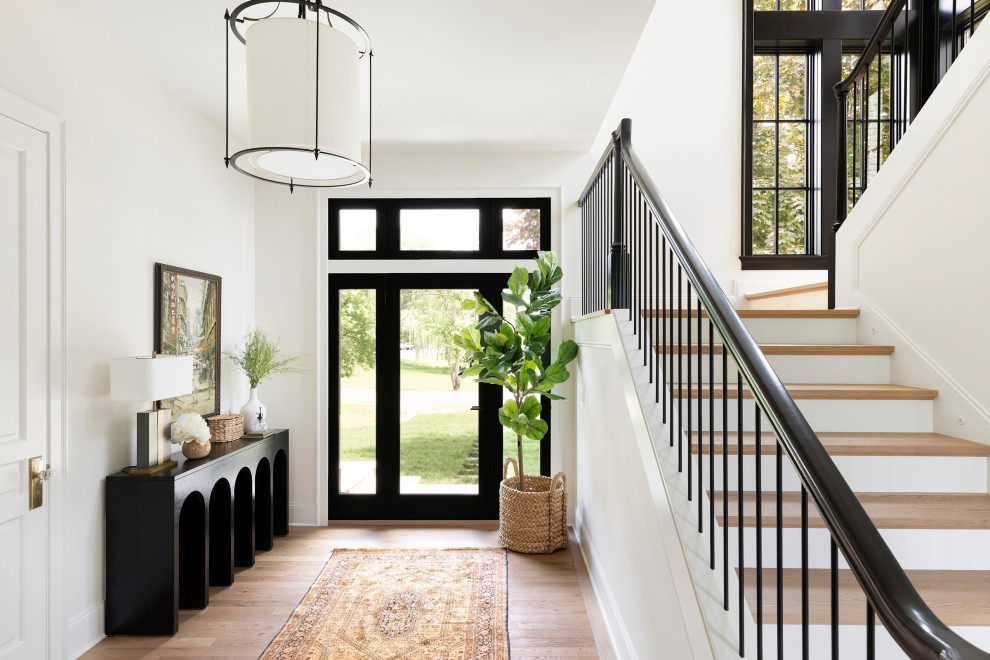 Example of a transitional medium tone wood floor and brown floor entryway design in Minneapolis with white walls and a glass front door