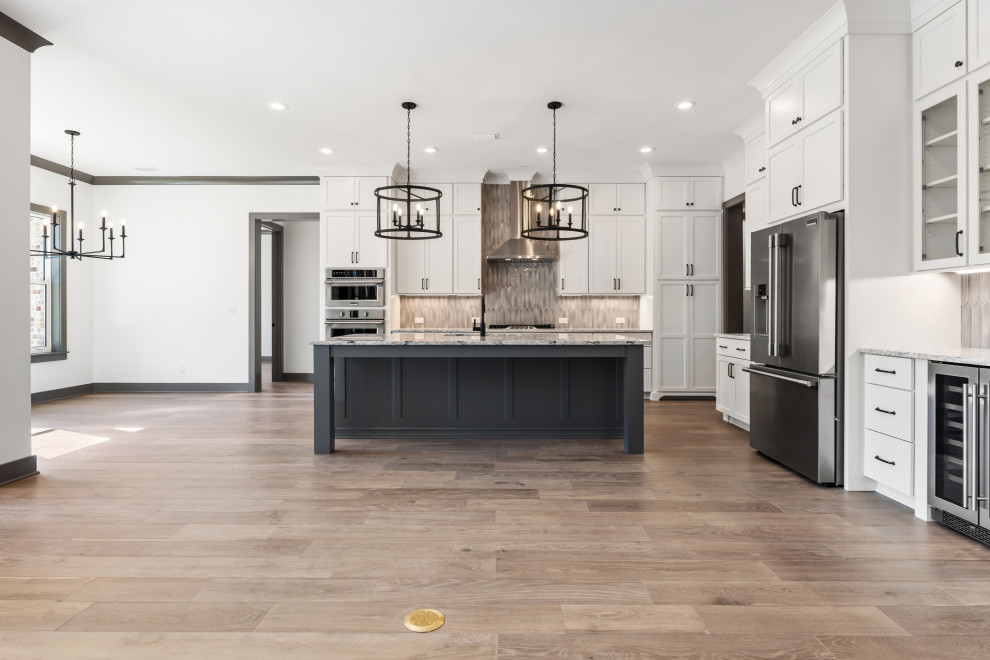 Open concept kitchen - mid-sized transitional l-shaped medium tone wood floor and brown floor open concept kitchen idea with recessed-panel cabinets, white cabinets, quartz countertops, beige backsplash, ceramic backsplash, stainless steel appliances and an island