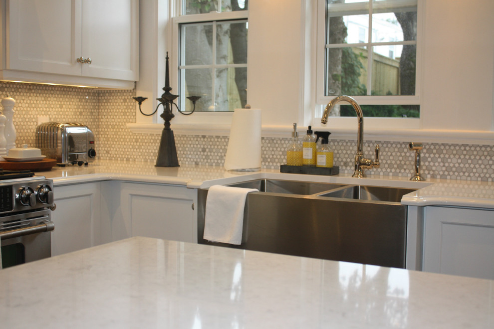 Example of a mid-sized transitional l-shaped kitchen design with shaker cabinets, white cabinets, white backsplash, stainless steel appliances, an island, a double-bowl sink and mosaic tile backsplash