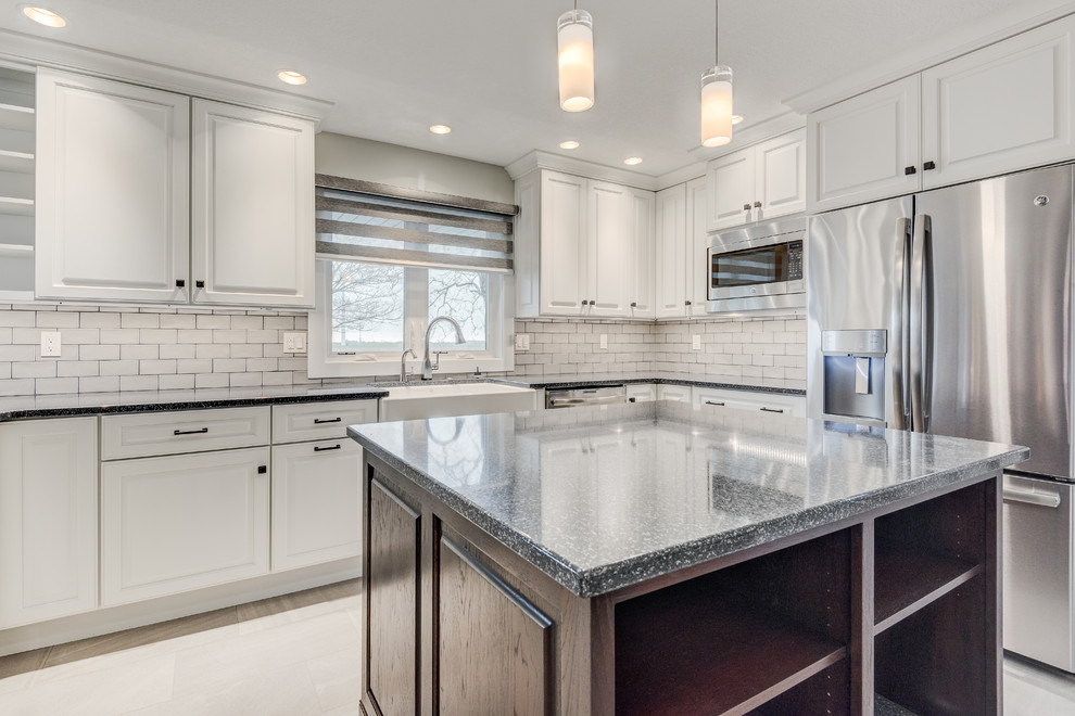Mid-sized transitional u-shaped eat-in kitchen in Chicago with a farmhouse sink, raised-panel cabinets, white cabinets, quartzite benchtops, grey splashback, glass tile splashback, stainless steel appliances, ceramic floors, with island and beige floor.
