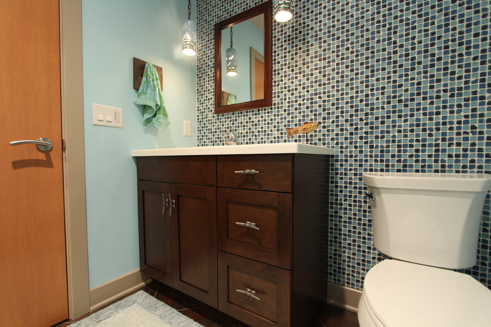 This is an example of a mid-sized transitional 3/4 bathroom in Other with shaker cabinets, dark wood cabinets, an alcove shower, a two-piece toilet, blue tile, glass sheet wall, blue walls, concrete floors, an undermount sink and engineered quartz benchtops.