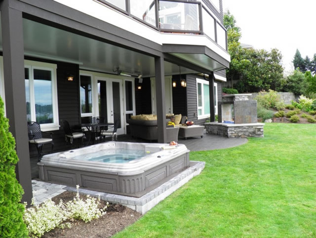 This is an example of a large traditional backyard deck in Seattle with a roof extension and a fire feature.