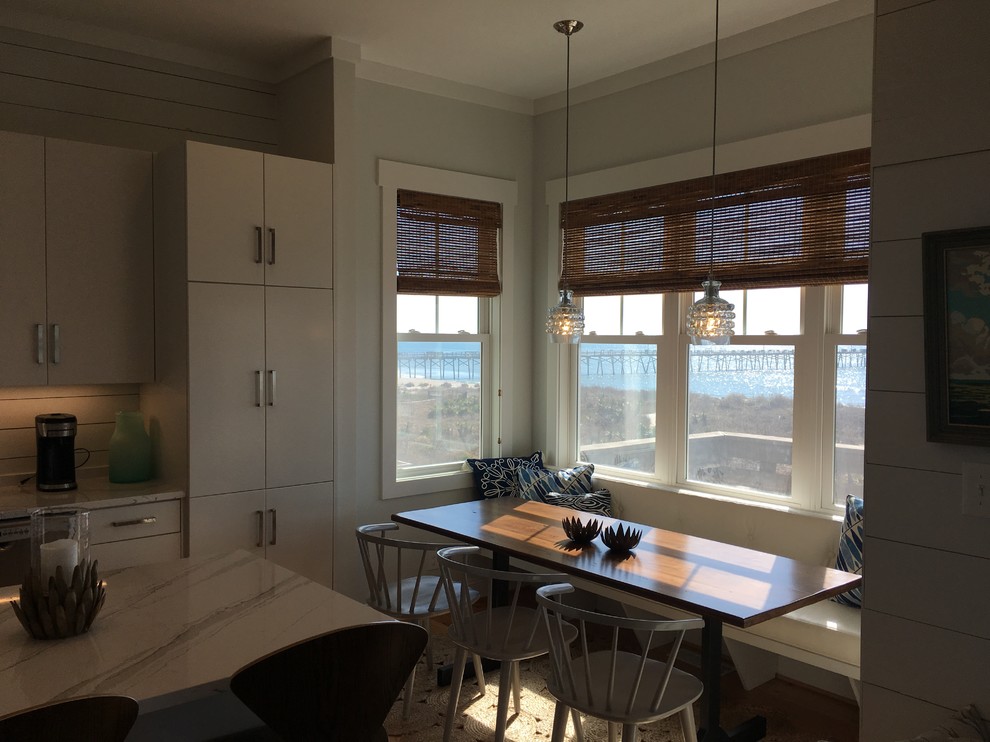 Design ideas for a beach style l-shaped kitchen in Other with flat-panel cabinets, white cabinets, quartzite benchtops, white splashback, timber splashback, stainless steel appliances, medium hardwood floors and with island.