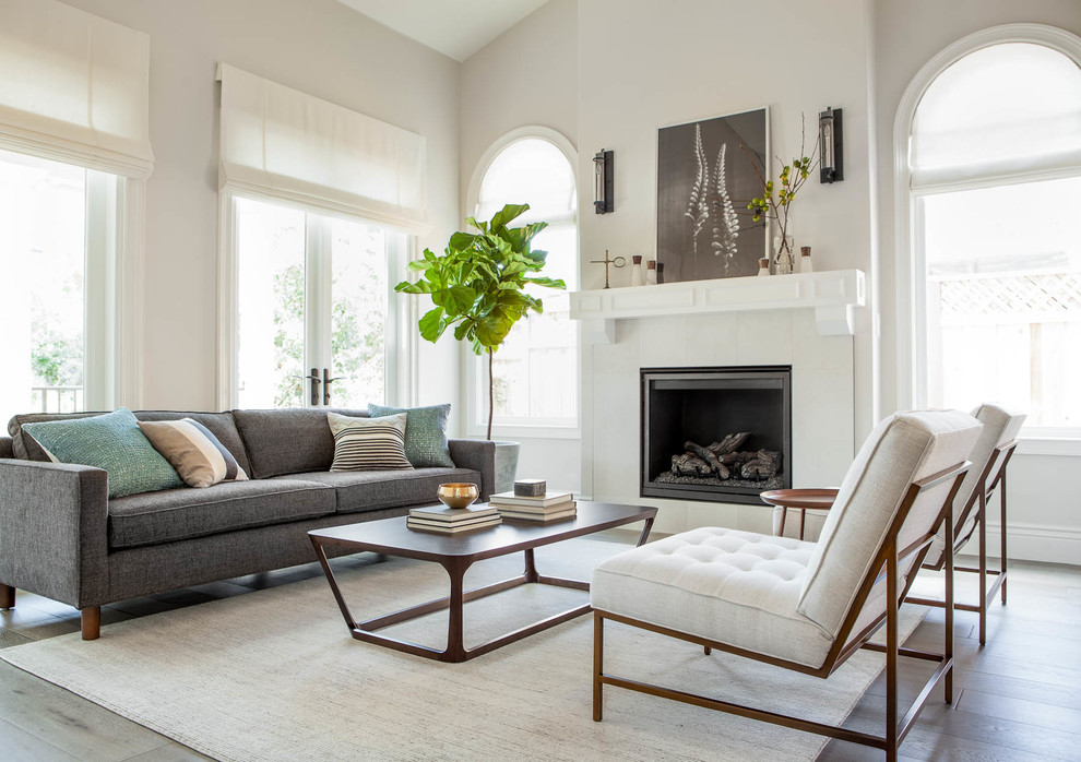 Photo of a transitional formal living room in San Francisco with grey walls, medium hardwood floors, a standard fireplace, a stone fireplace surround and no tv.