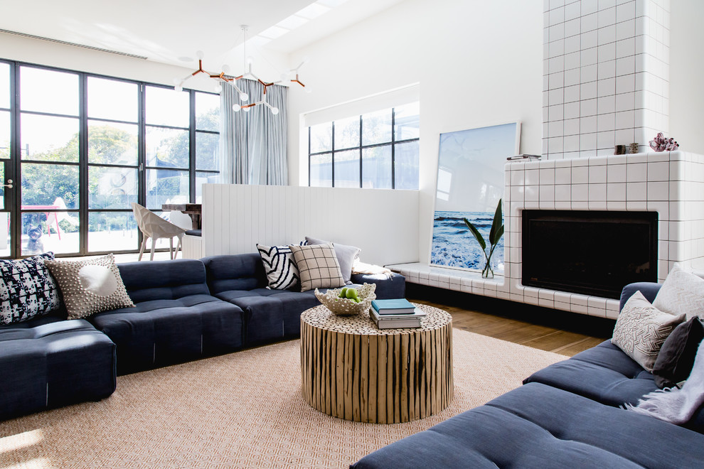 This is an example of a large contemporary open concept family room in Brisbane with white walls, light hardwood floors, a standard fireplace and a stone fireplace surround.