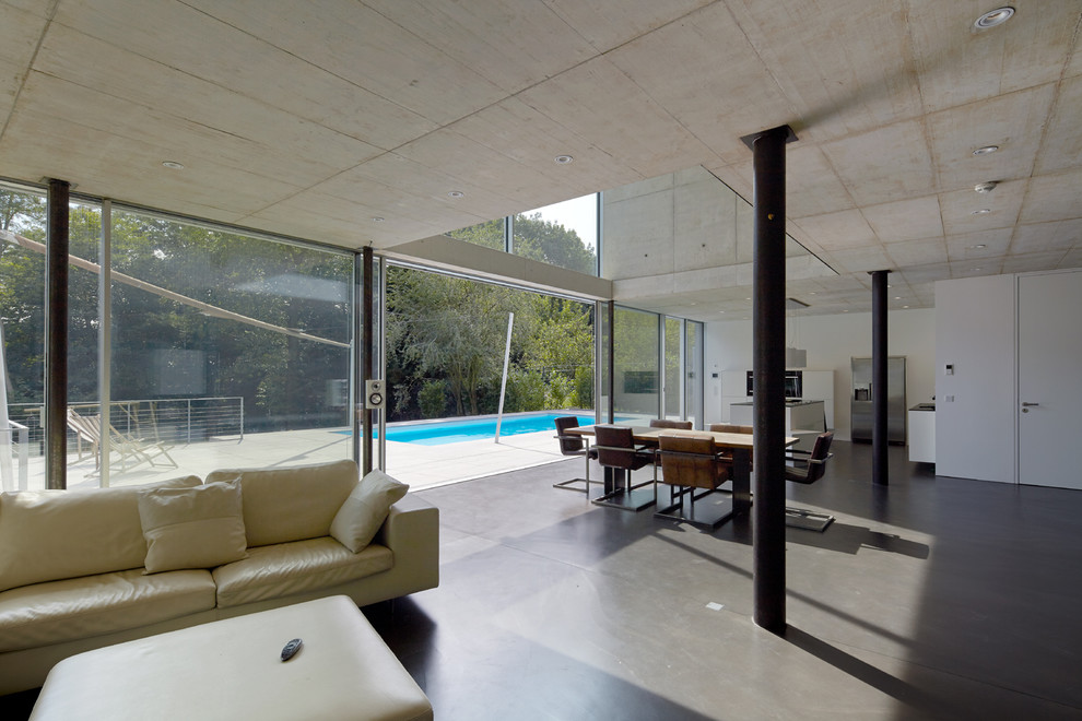 Geräumiges, Offenes Modernes Wohnzimmer mit weißer Wandfarbe und Betonboden in Düsseldorf