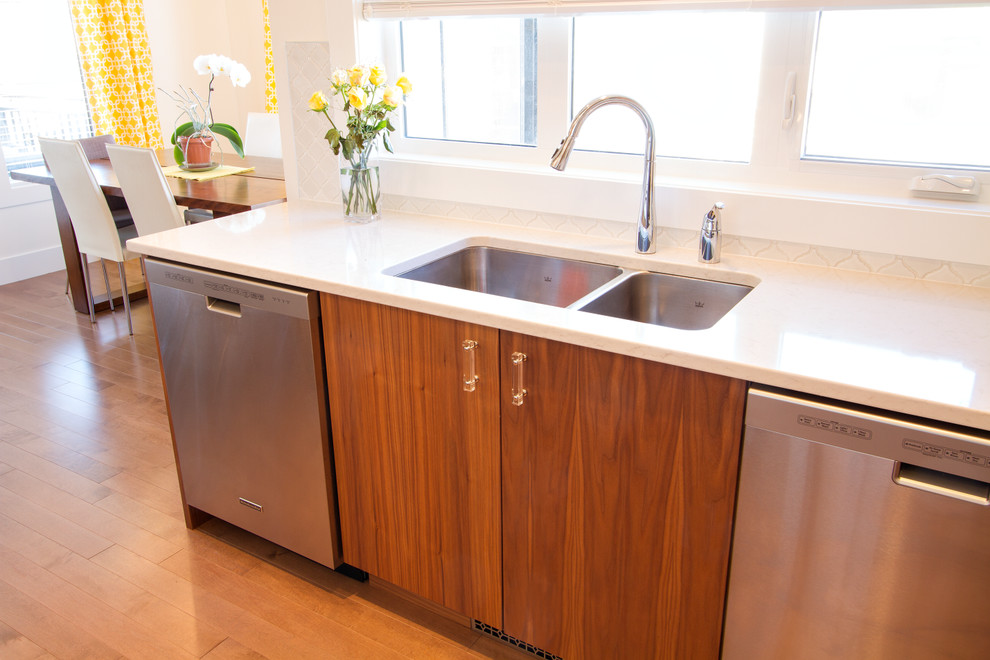 Large minimalist l-shaped medium tone wood floor eat-in kitchen photo with an undermount sink, flat-panel cabinets, medium tone wood cabinets, quartz countertops, white backsplash, ceramic backsplash, stainless steel appliances and an island