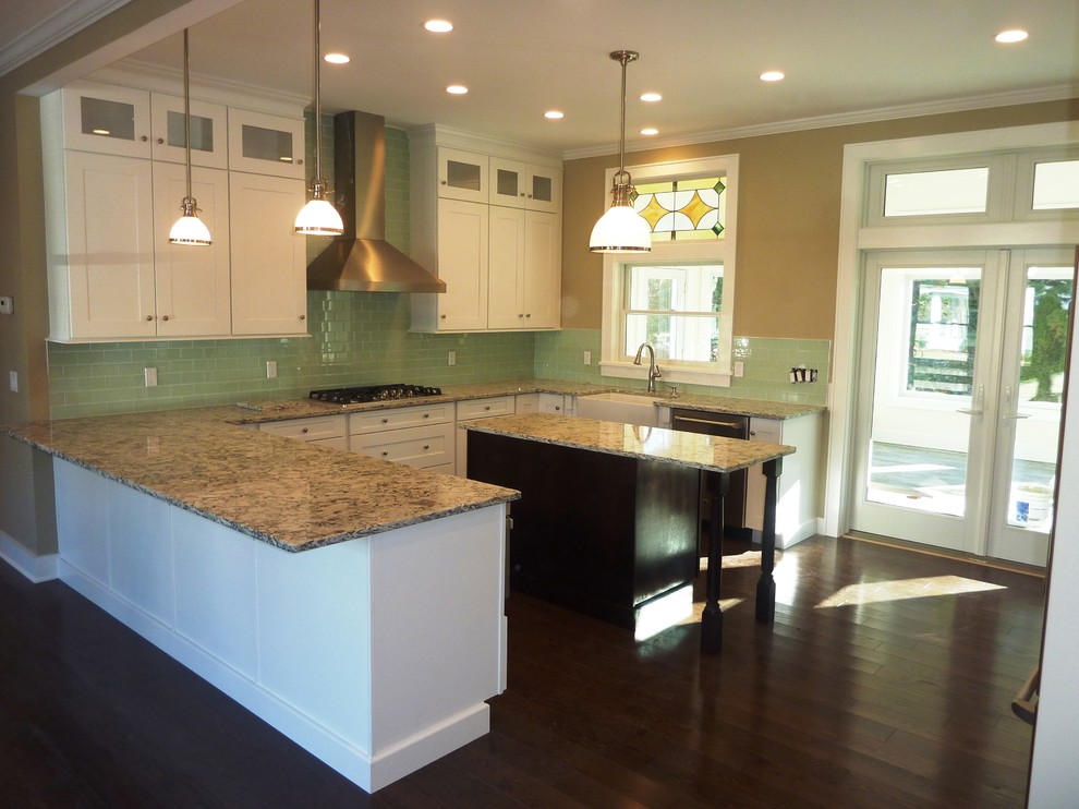 This is an example of a large traditional u-shaped eat-in kitchen in New York with a farmhouse sink, shaker cabinets, white cabinets, quartz benchtops, green splashback, glass tile splashback, stainless steel appliances, dark hardwood floors and with island.