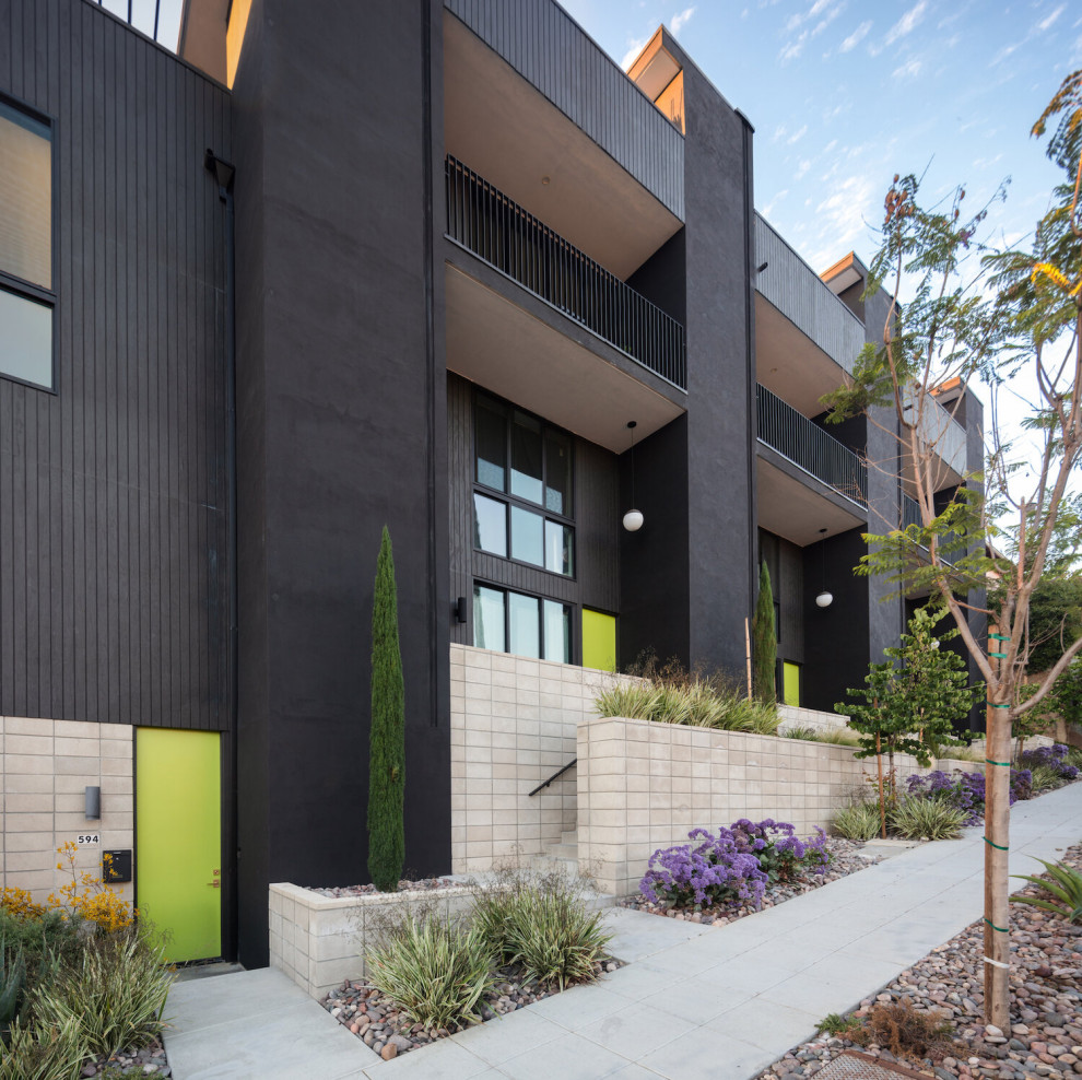 Photo of a midcentury black townhouse exterior in San Diego with four or more storeys, wood siding, a flat roof, a mixed roof and a white roof.