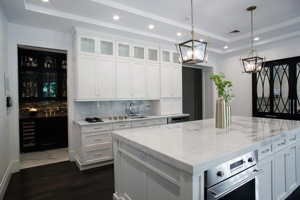 This is an example of an expansive transitional u-shaped eat-in kitchen in New York with an undermount sink, recessed-panel cabinets, white cabinets, quartzite benchtops, white splashback, stone tile splashback, stainless steel appliances, medium hardwood floors and with island.