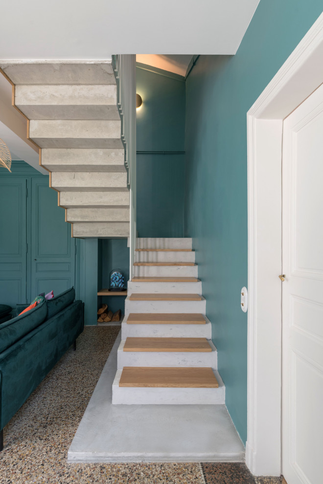 Large transitional wood u-shaped staircase in Lyon with concrete risers and metal railing.