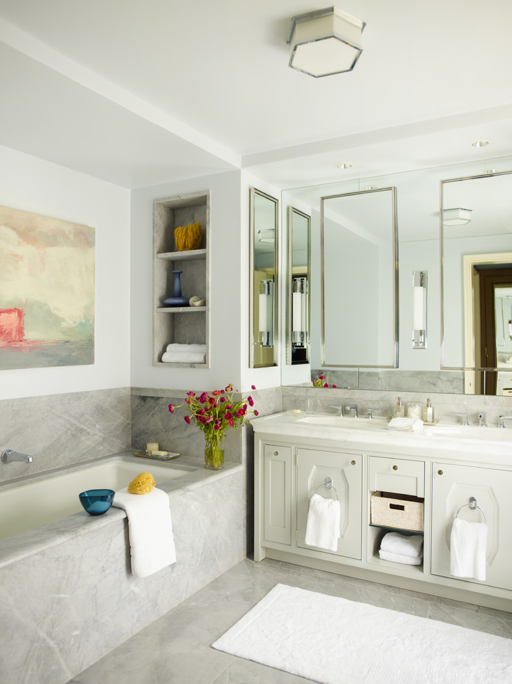 Photo of a transitional bathroom in New York with shaker cabinets, grey cabinets, an alcove tub, gray tile and a niche.