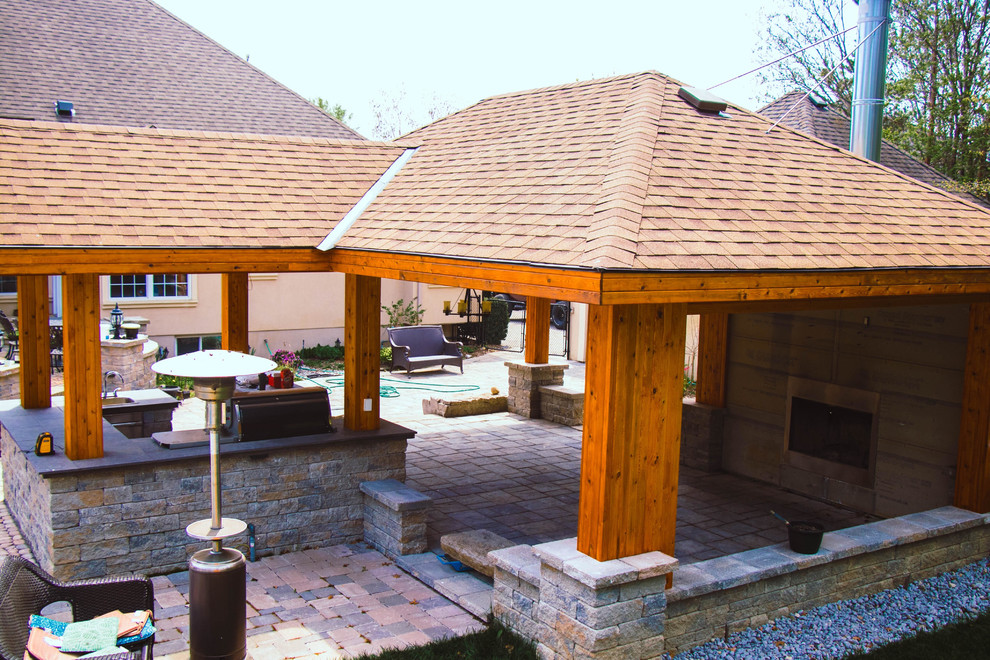 Photo of a large transitional backyard patio in Toronto with an outdoor kitchen, natural stone pavers and a gazebo/cabana.