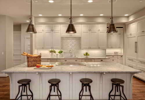 Large white kitchen with pewter pendant lights and four backless swivel bar stools in pewter