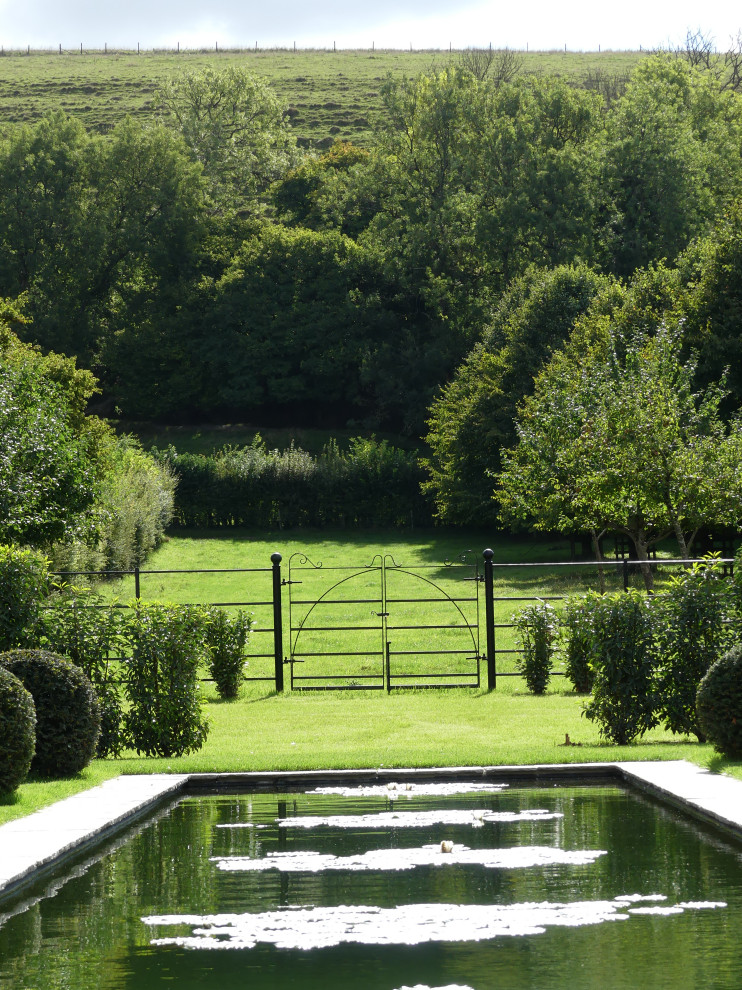 Réalisation d'un grand jardin à la française arrière design avec une cascade, une exposition ensoleillée et des pavés en pierre naturelle.