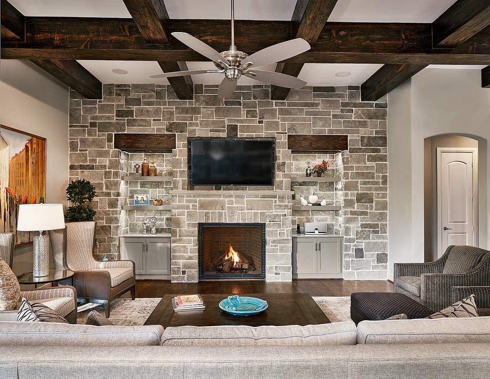 Inspiration for a large transitional family room in Dallas with grey walls, dark hardwood floors, a standard fireplace, a stone fireplace surround and a wall-mounted tv.
