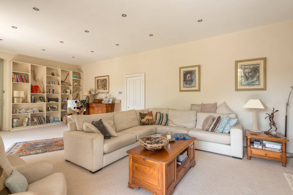 This is an example of a large contemporary formal enclosed living room in Devon with beige walls, carpet, a hanging fireplace and a freestanding tv.